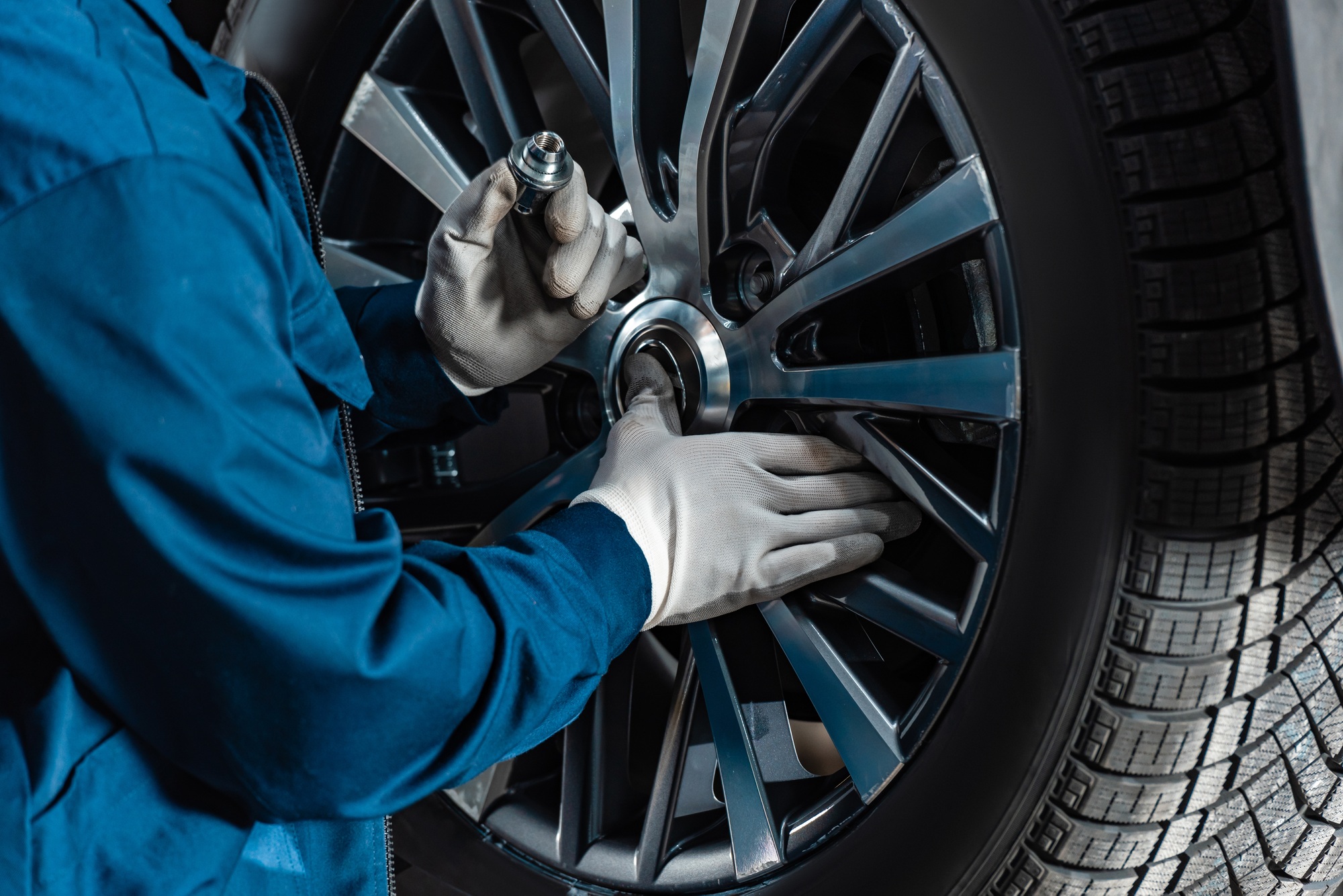 cropped view of mechanic fixing wheel on car in workshop, Serviços de Auto Socorro em São Paulo