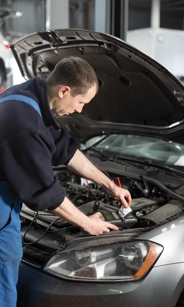 Male hands holding modern utility and checking voltage of automobile battery, Serviços de Auto Socorro em São Paulo